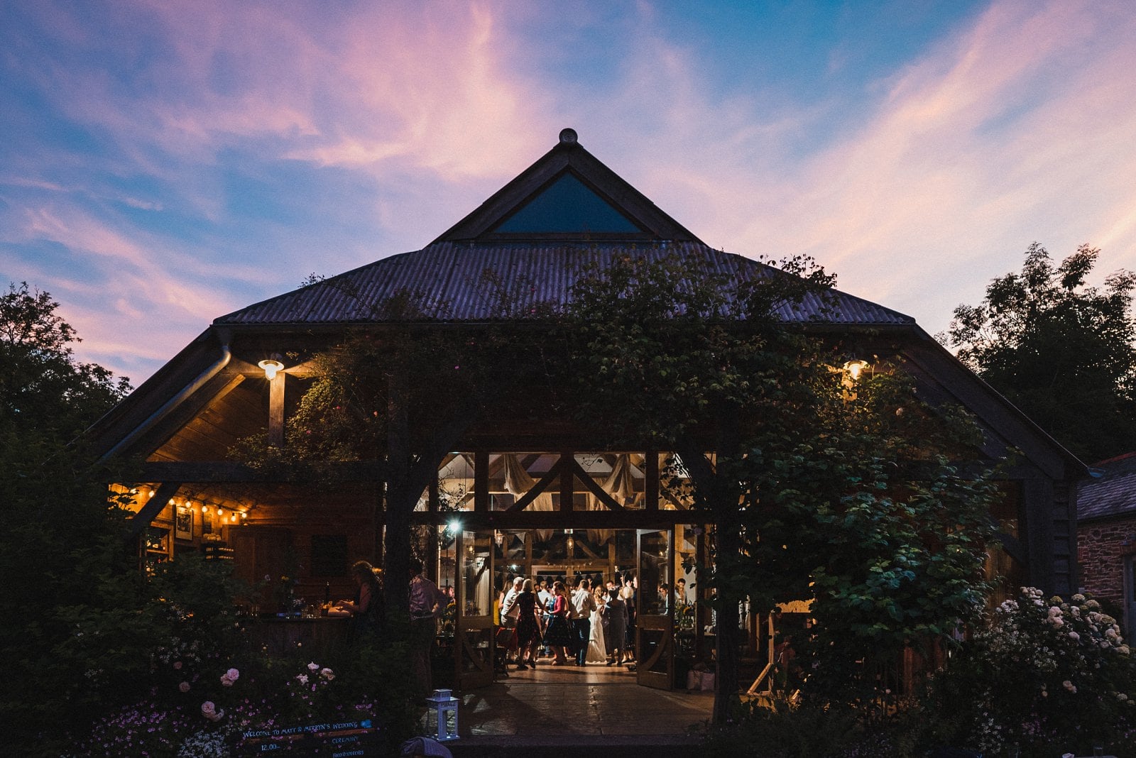 The Oak Barn at Nancarrow Farm with the party in full swing inside and the sun setting outside